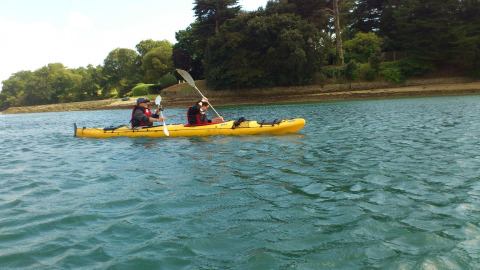 Dos personas remando en kayak amarillo sobre el agua en Flower Camping Le Conleau, Bretaña, Francia.