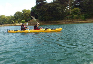 Dos personas remando en kayak amarillo sobre el agua en Flower Camping Le Conleau, Bretaña, Francia.