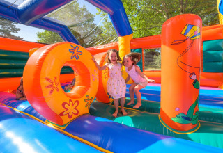 Dos niños juegan juntos en un colorido castillo hinchable en Flower Camping Le Conleau, Bretaña, Francia.