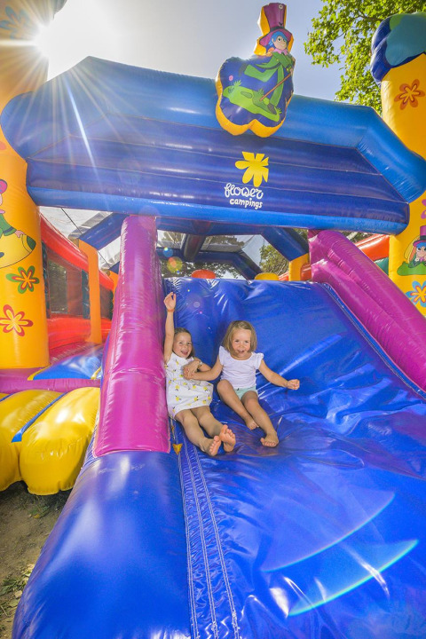 Dos niños juegan en un tobogán inflable en Flower Camping Le Conleau, Bretaña, Francia, en un día soleado.