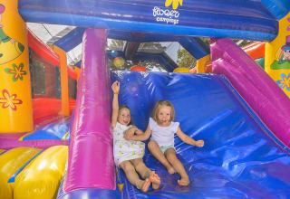 Due bambini si divertono su uno scivolo gonfiabile al Flower Camping Le Conleau, Bretagna, Francia.