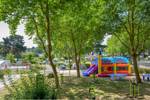Parque infantil con castillo inflable y árboles en Flower Camping Le Conleau en Bretaña, Francia.