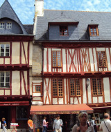 Bindingsværkshuse i den gamle bydel i Vannes, Bretagne, Frankrig, med travle gående og butikker foran.