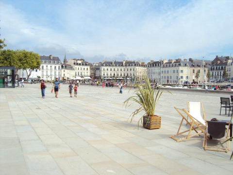Plaza scene at Flower Camping Le Conleau holiday park in Brittany, France, with people and historic buildings.