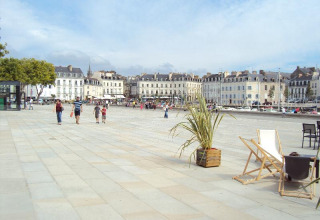 Plaza scene at Flower Camping Le Conleau holiday park in Brittany, France, with people and historic buildings.