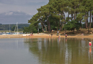 People enjoying the waterfront and trees at Flower Camping Le Conleau holiday park in Brittany, France.