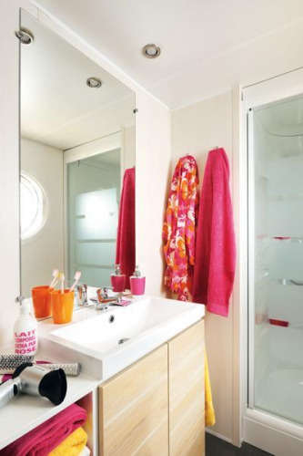 Bathroom in a glamping accommodation with colorful towels, modern sink unit, and glass shower cabin.