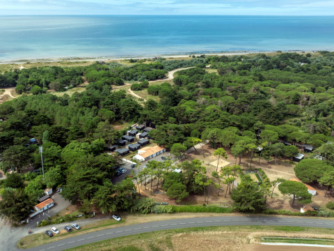 Vista aerea di Flower Camping Tamarins Plage tra boschi, bungalow e mare in Nouvelle-Aquitaine, Francia.