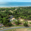 Aerial view of Flower Camping Tamarins Plage showing forest, cabins, and seaside in Nouvelle-Aquitaine, France.