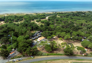 Aerial view of Flower Camping Tamarins Plage showing forest, cabins, and seaside in Nouvelle-Aquitaine, France.