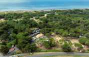 Aerial view of Flower Camping Tamarins Plage showing forest, cabins, and seaside in Nouvelle-Aquitaine, France.