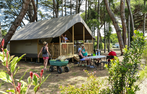 Familia disfruta en una tienda safari Tente Lodge Confort en Flower Camping Tamarins Plage, Francia, rodeada de naturaleza.