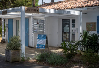 Receptie van Flower Camping Tamarins Plage, een vakantiepark met witte gebouwen in Frankrijk.