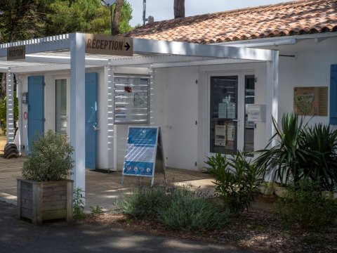 Receptie van Flower Camping Tamarins Plage, een vakantiepark met witte gebouwen in Frankrijk.