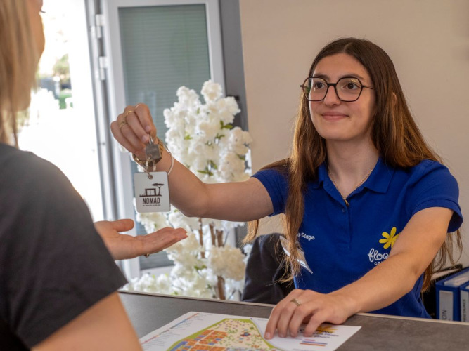 La receptionist consegna una chiave a un ospite al Flower Camping Tamarins Plage in Nouvelle-Aquitaine, Francia.