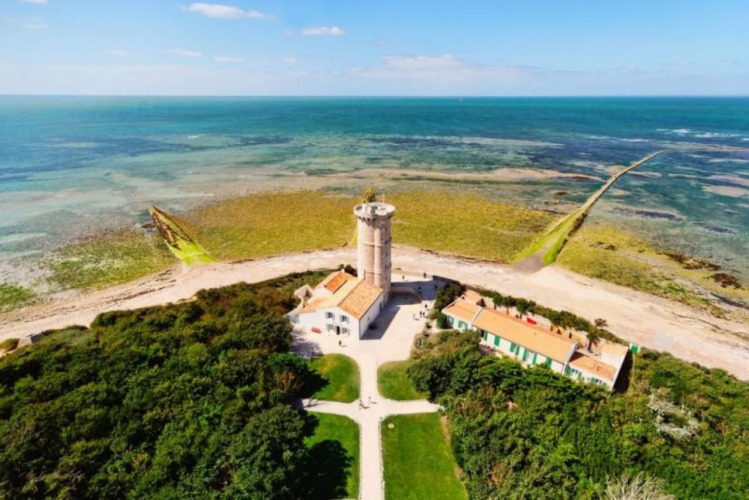 Vista aérea de un faro cerca de Le Bois-Plage-en-Ré, Francia, rodeado de océano y zonas verdes.
