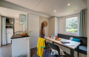 Modern glamping accommodation featuring a compact kitchen, dining table, large window, and cozy decor.