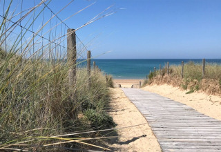 Pasarela de madera en las dunas hacia la playa y el mar en Flower Camping Tamarins Plage, Nouvelle-Aquitaine, Francia.