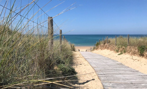 Chemin en bois à travers les dunes vers la plage de Flower Camping Tamarins Plage, Nouvelle-Aquitaine, France.