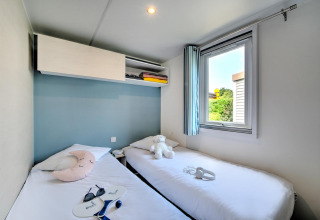 Kamer met twee enkele bedden, een raam, zachte kussens en een modern glampinginterieur.