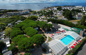 Vista aerea del Flower Camping Le Bois d'Amour con piscina, alberi e mare in Bretagna, Francia.