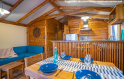Innenaufnahme der Lodge Premium VIP bei Flower Camping L'Ile d'Offard mit Holzmöbeln und Esstisch.