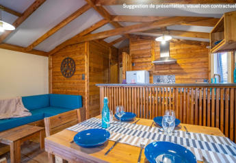 Vista interna della Lodge Premium VIP presso Flower Camping L'Ile d'Offard con arredi in legno e tavolo da pranzo.