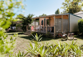 Cabañas de madera con porches y bicicletas fuera en Flower Camping Le Bois d'Amour, parque vacacional en Bretaña, Francia.
