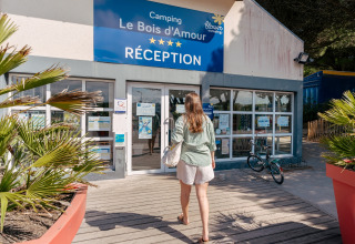 Mujer entrando en la recepción de Flower Camping Le Bois d'Amour, parque turístico en Bretaña, Francia.