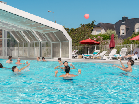 Des vacanciers profitent de la piscine et des transats au Flower Camping Le Bois d'Amour en Bretagne.