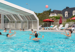 Guests enjoying the swimming pool and sun loungers at Flower Camping Le Bois d'Amour in Brittany, France.