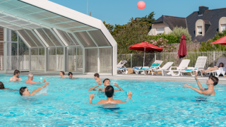 Gæster nyder poolen og solbadning ved Flower Camping Le Bois d'Amour i Bretagne, Frankrig, om sommeren.