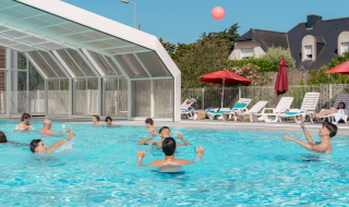 Gäste genießen den Pool und die Sonnenliegen im Flower Camping Le Bois d'Amour, Bretagne, Frankreich.