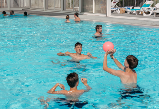Niños juegan con una pelota en la piscina del Flower Camping Le Bois d'Amour en Bretaña, Francia.