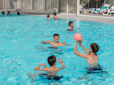 Niños juegan con una pelota en la piscina del Flower Camping Le Bois d'Amour en Bretaña, Francia.