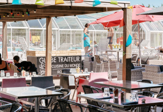 Terraza de restaurante al aire libre con vista a la piscina en Flower Camping Le Bois d'Amour, Bretaña, Francia.