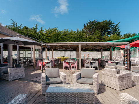 Ruim buitenterras met zit- en eetgedeelte bij Flower Camping Le Bois d'Amour in Bretagne, Frankrijk.