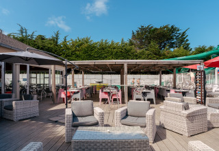Grande terrasse extérieure avec salon et coin repas au Flower Camping Le Bois d'Amour en Bretagne, France.