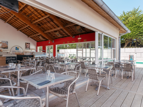 Outdoor café seating with metal furniture at Flower Camping Le Bois d'Amour, a holiday park in Brittany, France.