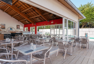 Espace café extérieur avec tables et chaises métalliques au Flower Camping Le Bois d'Amour, en Bretagne, France.