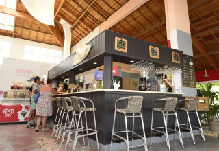 Bar area at Flower Camping Le Bois d'Amour, Brittany, France, featuring guests and modern interior design.