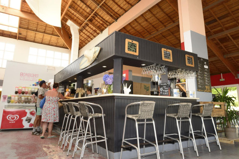 Espace bar au Flower Camping Le Bois d'Amour en Bretagne, France, avec clients et décoration contemporaine.