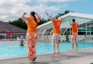 Tre persone saltano insieme in piscina a Flower Camping Le Bois d'Amour, villaggio vacanze in Bretagna, Francia.