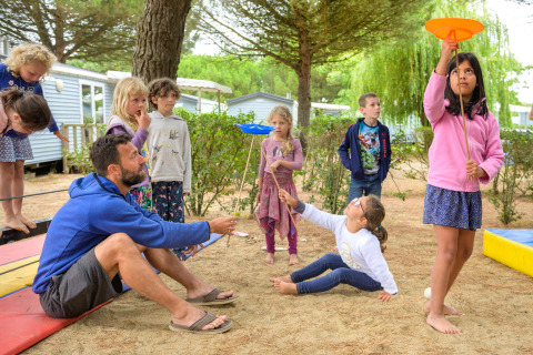Bambini e un adulto giocano all'aperto a Flower Camping Le Bois d'Amour in Bretagna, Francia.