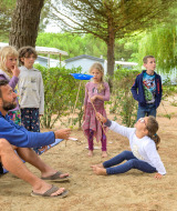 Kinder und ein Erwachsener spielen zusammen im Freien im Flower Camping Le Bois d'Amour, Bretagne, Frankreich.