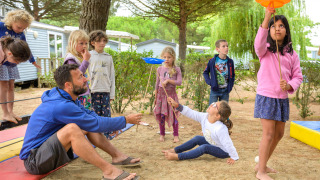 Børn og en voksen leger sammen i det fri på Flower Camping Le Bois d'Amour, Bretagne, Frankrig.