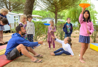 Kinderen en een volwassene spelen buiten op Flower Camping Le Bois d'Amour in Bretagne, Frankrijk.