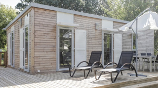 Vue extérieure du lodge Stacaravan Premium avec terrasse en bois, transats et coin repas extérieur.