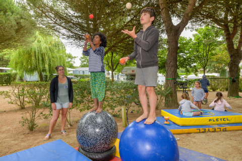 Children juggle while balancing on large balls at Flower Camping Le Bois d'Amour holiday park in Brittany.