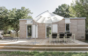 Lodge en bois avec terrasse, parasol et salon de jardin à Flower Camping L'Ile d'Offard, France.
